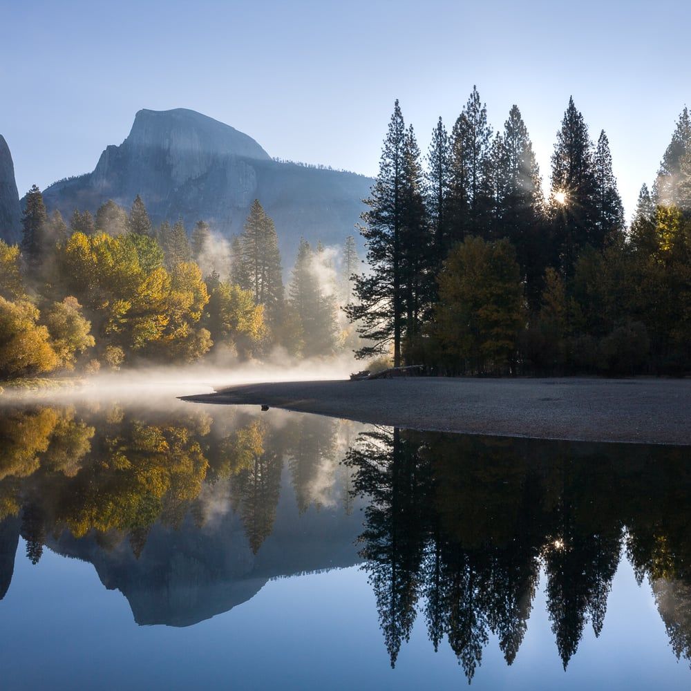 Half Dome at dawn with mist rising off the Merced River and autumn trees reflected in still water, Yosemite, by Michael Frye
